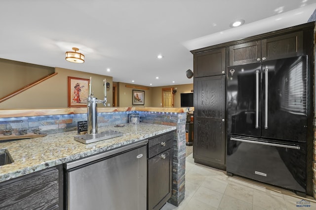 kitchen featuring light stone counters, light tile patterned flooring, recessed lighting, dark brown cabinets, and freestanding refrigerator