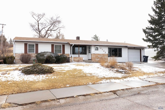 ranch-style house with stone siding, an attached garage, and driveway