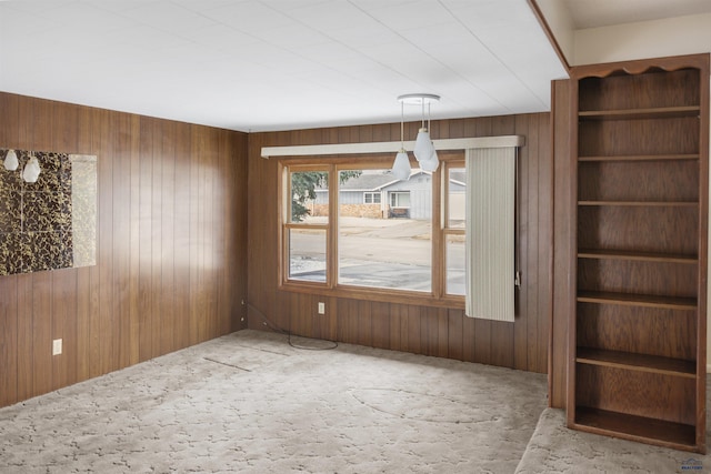 unfurnished living room featuring carpet flooring and wooden walls