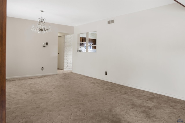 carpeted spare room with baseboards, visible vents, and a chandelier