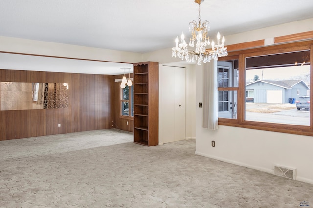 carpeted spare room featuring visible vents and wood walls