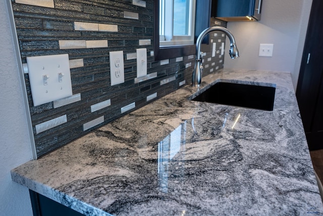 room details featuring stone countertops, a sink, and backsplash