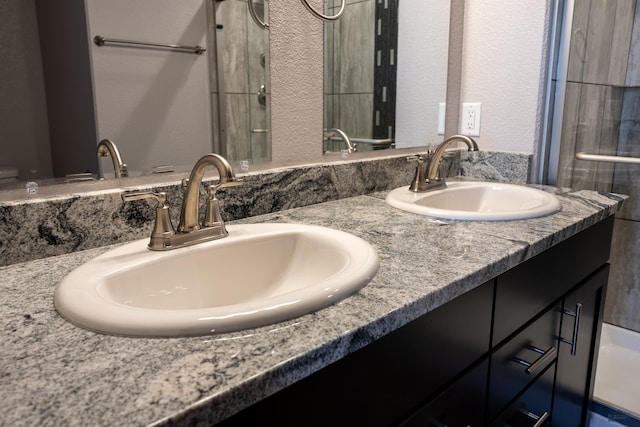 full bath featuring double vanity, a sink, and a textured wall