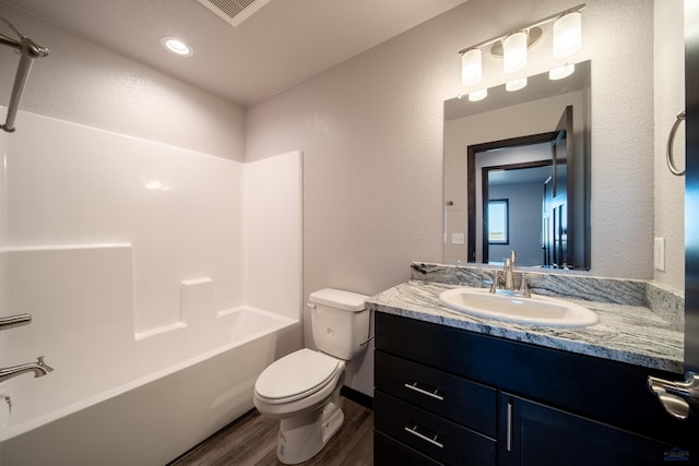 full bath with visible vents, toilet, wood finished floors,  shower combination, and vanity