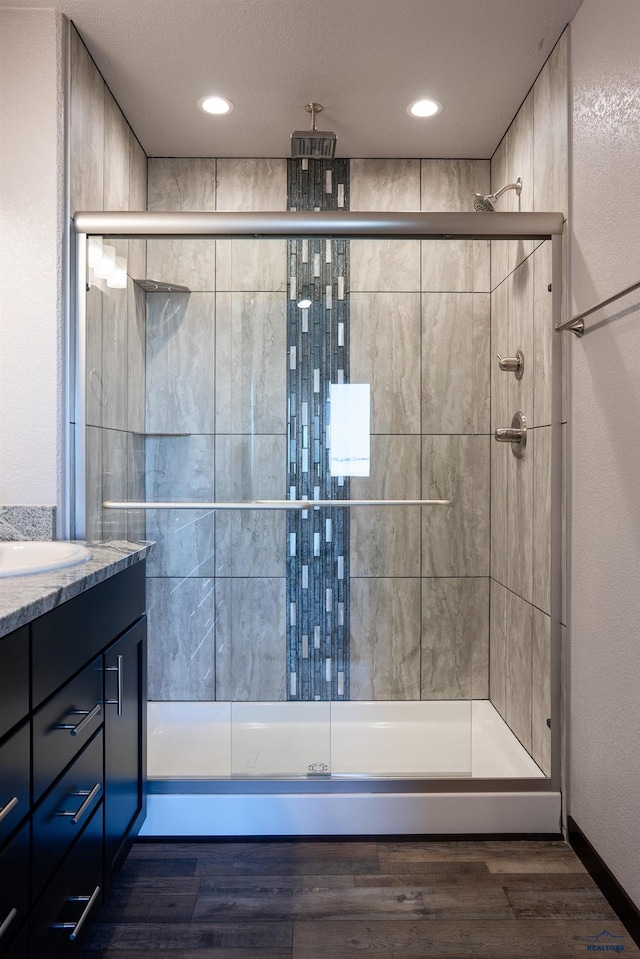 bathroom featuring recessed lighting, a shower stall, wood finished floors, and vanity