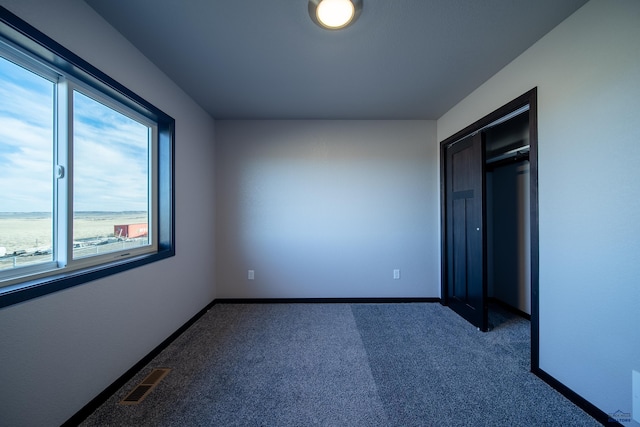 unfurnished bedroom featuring baseboards, visible vents, and dark carpet