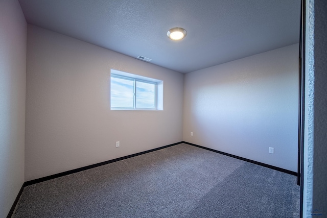 carpeted spare room featuring visible vents, a textured ceiling, and baseboards