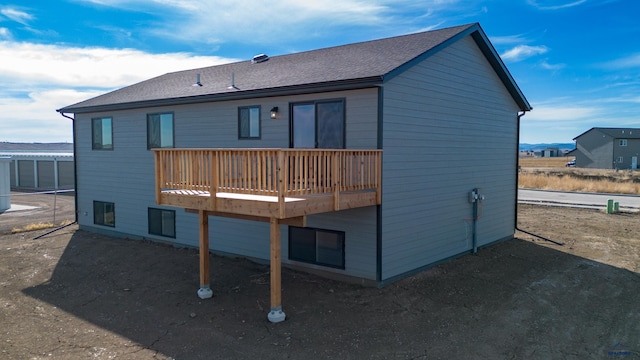 back of property featuring a deck and roof with shingles