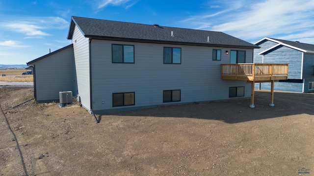 back of house with central AC and roof with shingles