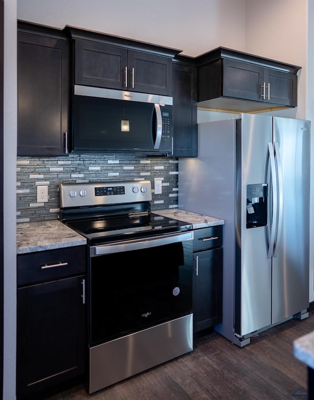 kitchen featuring light stone countertops, dark wood-style floors, tasteful backsplash, and stainless steel appliances