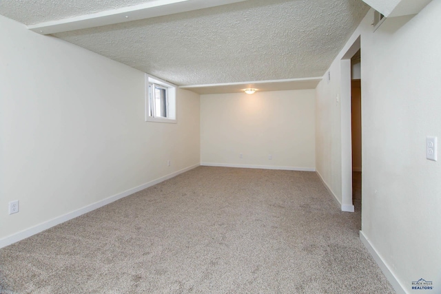 basement featuring carpet, baseboards, and a textured ceiling