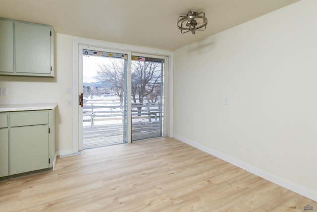 unfurnished dining area with light wood finished floors and baseboards