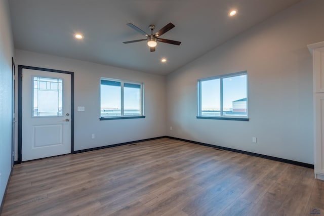 empty room featuring recessed lighting, vaulted ceiling, and wood finished floors