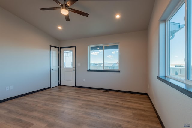 empty room with lofted ceiling, recessed lighting, wood finished floors, and baseboards