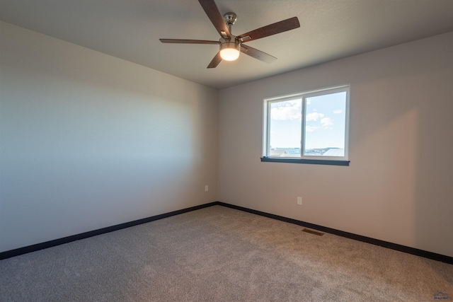 carpeted spare room with visible vents, ceiling fan, and baseboards