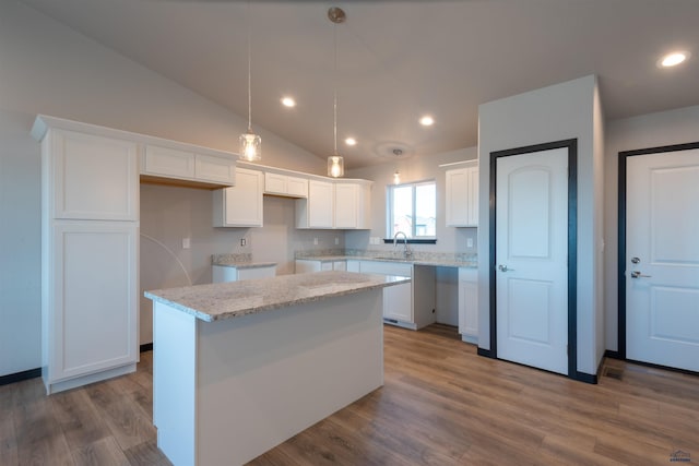 kitchen featuring recessed lighting, white cabinetry, vaulted ceiling, a sink, and wood finished floors