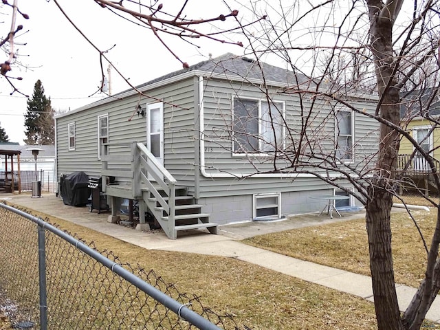 rear view of house featuring a garage and fence