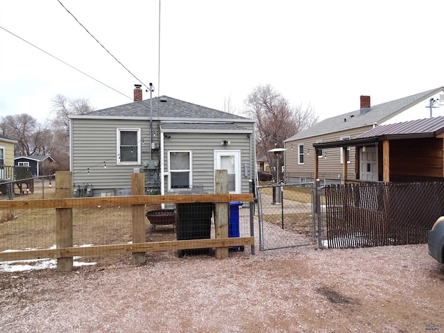 back of property with a shingled roof, a chimney, and fence