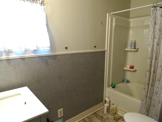 bathroom with toilet, tile walls, and shower / tub combo with curtain