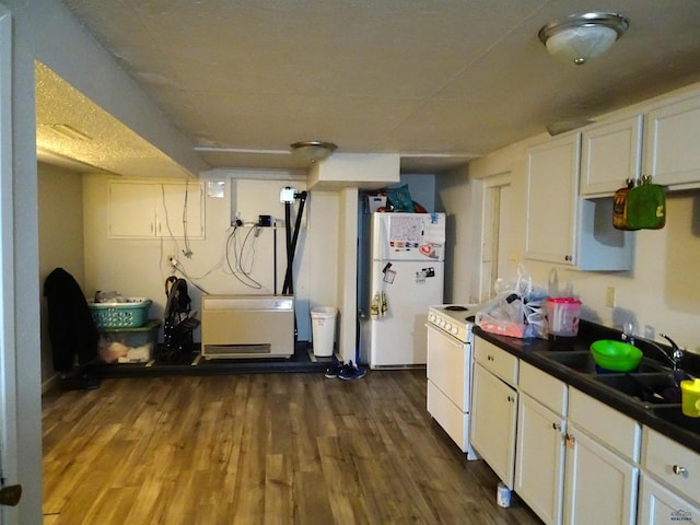 kitchen with white appliances, a sink, white cabinets, dark wood-style floors, and dark countertops