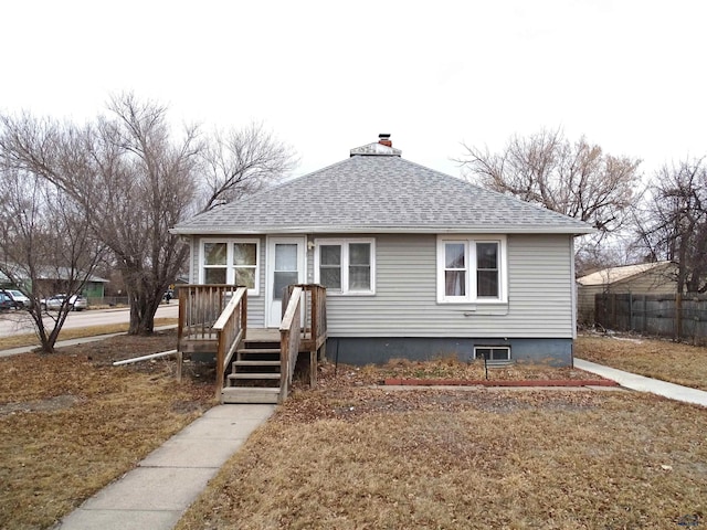 bungalow with roof with shingles, a chimney, a wooden deck, and fence