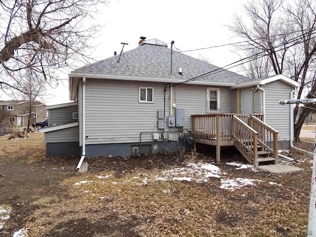 rear view of house featuring roof with shingles