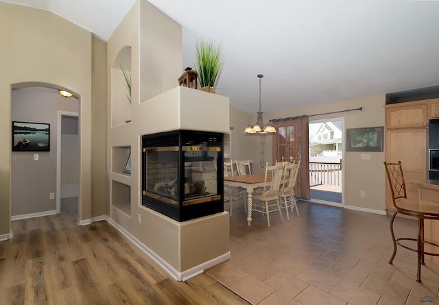 dining area with arched walkways, vaulted ceiling, a chandelier, and baseboards