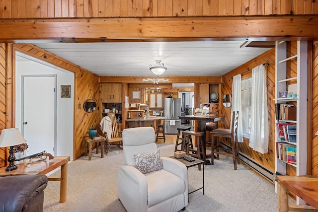 living area with wooden walls, a baseboard radiator, and light colored carpet