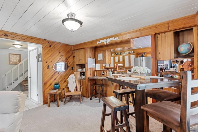 dining room featuring wooden walls, stairway, and light colored carpet