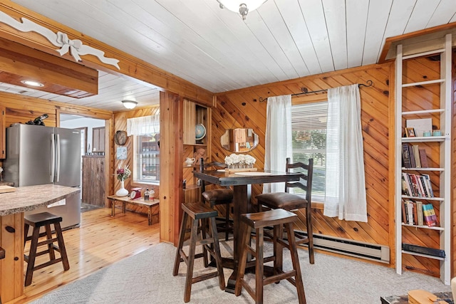 dining space with wooden ceiling, a baseboard radiator, wooden walls, and light wood-style flooring