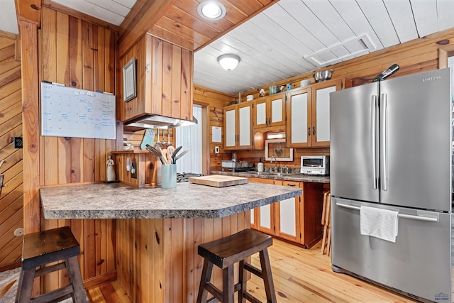 kitchen with visible vents, freestanding refrigerator, wood walls, wooden ceiling, and a peninsula