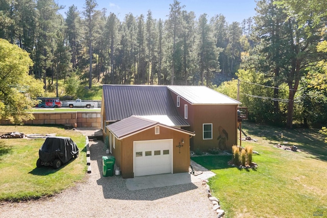 view of front of house with a garage, metal roof, a front lawn, and driveway