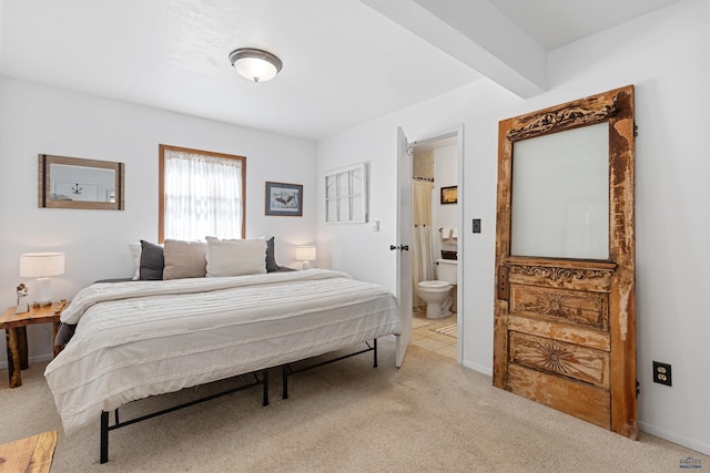 bedroom with beam ceiling, light carpet, baseboards, and ensuite bathroom