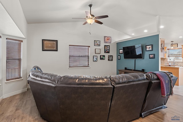 living area with baseboards, lofted ceiling, light wood-style flooring, ceiling fan, and recessed lighting