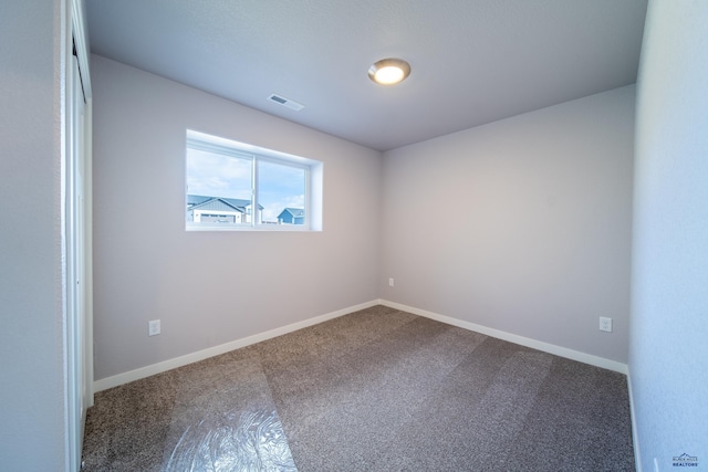 empty room with carpet, visible vents, and baseboards