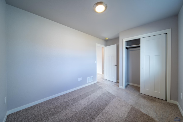 unfurnished bedroom featuring baseboards, a closet, visible vents, and carpet flooring