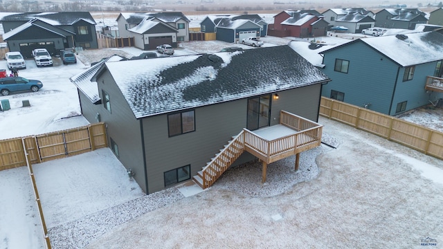 snow covered house featuring a residential view and fence