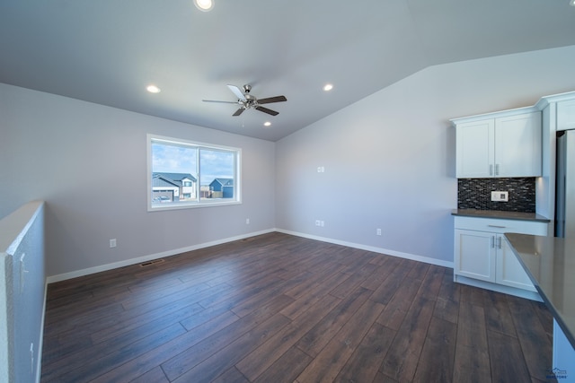 unfurnished living room with lofted ceiling, dark wood-style flooring, ceiling fan, and baseboards