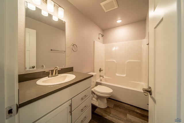 full bath with toilet, wood finished floors, vanity, visible vents, and washtub / shower combination