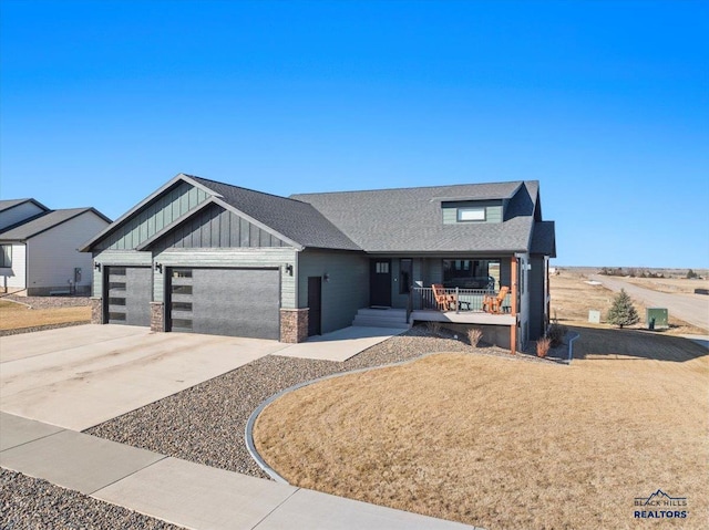 view of front of home with a garage, a shingled roof, concrete driveway, a porch, and board and batten siding