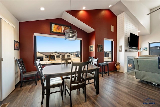 dining space featuring recessed lighting, high vaulted ceiling, wood finished floors, and a glass covered fireplace