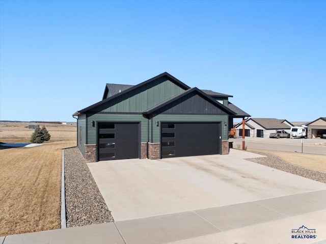 craftsman house with concrete driveway, stone siding, board and batten siding, and an attached garage