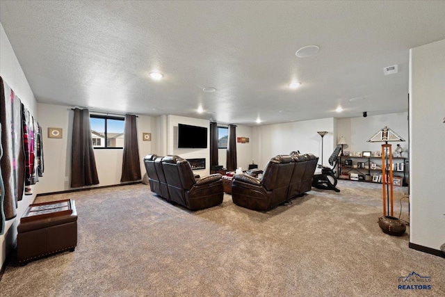 carpeted cinema room featuring a textured ceiling, a warm lit fireplace, visible vents, and baseboards