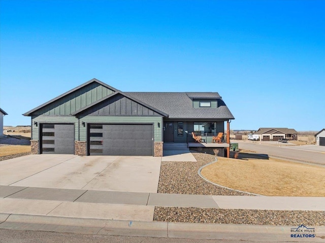 view of front of home with a garage, driveway, board and batten siding, and covered porch