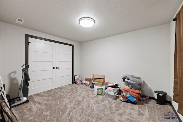 interior space featuring a textured ceiling, carpet, and visible vents