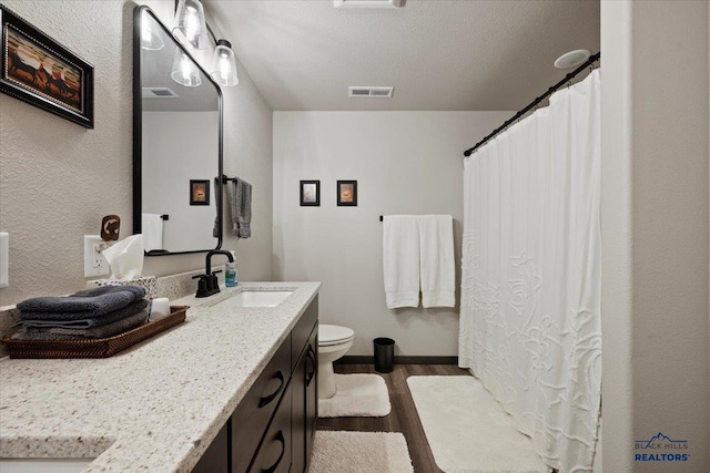 full bathroom with toilet, visible vents, wood finished floors, and vanity