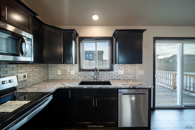 kitchen with tasteful backsplash, light stone countertops, stainless steel appliances, a sink, and recessed lighting