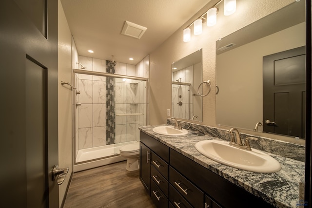 full bathroom featuring an enclosed shower, a sink, and wood finished floors