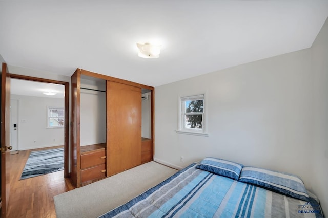 bedroom with multiple windows, light wood-style flooring, and baseboards