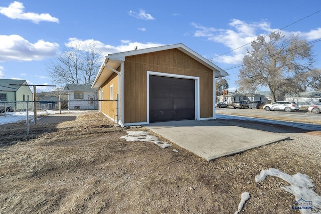 detached garage featuring a residential view, fence, and dirt driveway